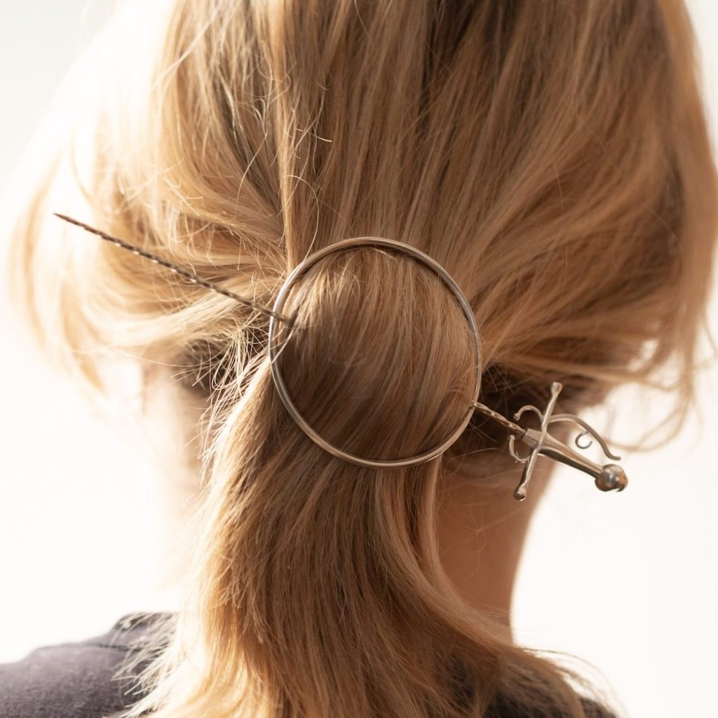 Back of woman's head showing a hairpin that looks like a sword.