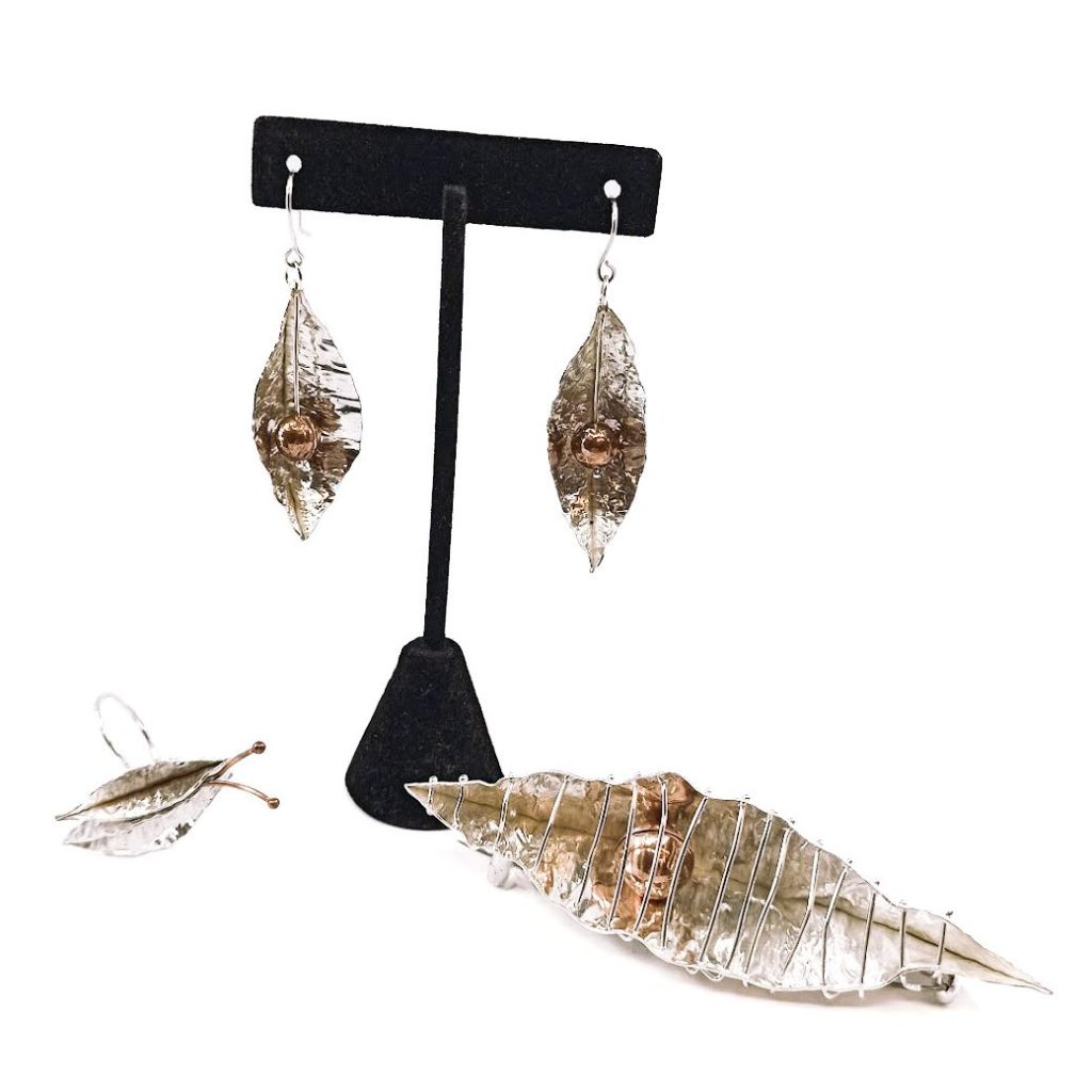 Jewellery set of earrings, a broach and a ring that look like silver pea pods.
